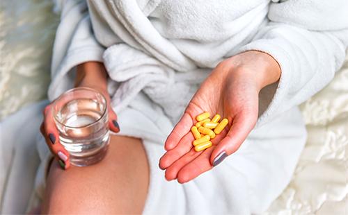 Девушка держит в руке желтые капсулы с лекарством